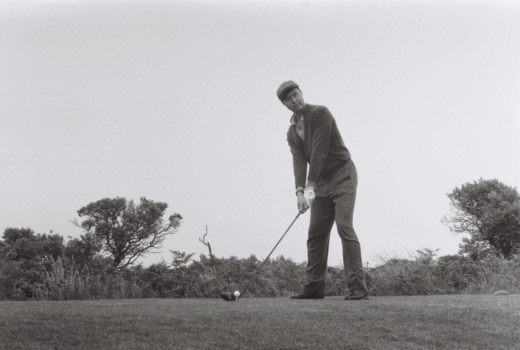 Nurtai Saldarov addressing his tee shot on a links course, in black and white